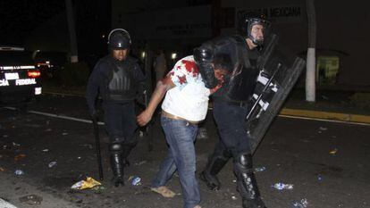 Un manifestante detenido por un polic&iacute;a en Acapulco. 