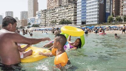 Mario (a la izquierda) juega con Alexander (centro) y Andrea (subida en el flotador), en el agua de la playa de Benidorm.
