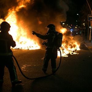 Bomberos de Barcelonas se disponen a sofocar uno de los incendios provocados por los manifestantes.