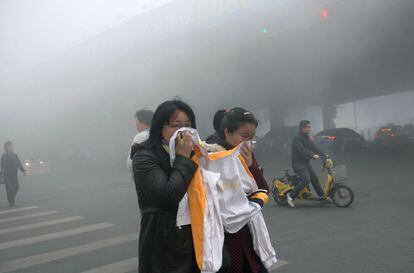 Unas mujeres en una calle de Harbin (China), 21 de octubre de 2013. Las autoridades meteorológicas han emitido una alerta roja, la de mayor gravedad, por la densa niebla tóxica en varias ciudades de la provincia a las 9:00 horas, pronosticando que el fenómeno se prolongará durante las próximas 24 horas.