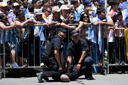 Policías detienen a un hombre que ha saltado la barricada que contiene a la multitud durante el recorrido de Milei, este domingo.