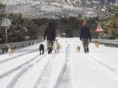 Una pareja camina por la carretera nevada que une Prado Negro con la A-92 en la provincia de Granada.