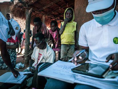 Rodeado por su mujer e hijos, Balança Manuel Sande rellena unos impresos que le han entregado los encuestadores del Centro de Investigación de Salud de Manhiça (CISM), en Mozambique, que colaboran con el Proyecto Bohemia.