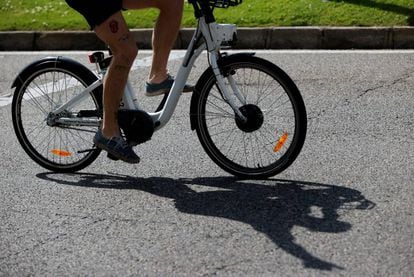 Una hombre transita la madrileña calle Alcalá con una bicicleta del servicio público Bicimad el Día Mundial de la Bicicleta