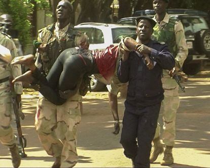 Personal militar de Mali traslada a una mujer herida a su salida del hotel.
