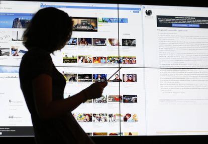 Una usuaria consulta una tableta frente a una pantalla con la página de Youtube.