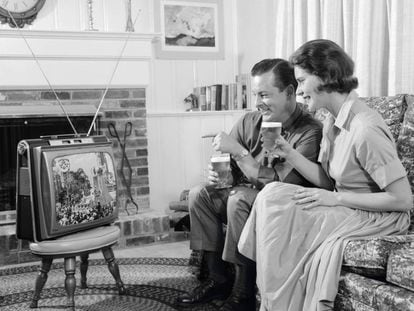 Una pareja mira su televisión portátil en una fotografía tomada en los años sesenta.
