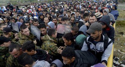 Decenas de refugiados intentan pasar una barrera de policías para subir a un autobús en Gevgelija en Macedonia.
