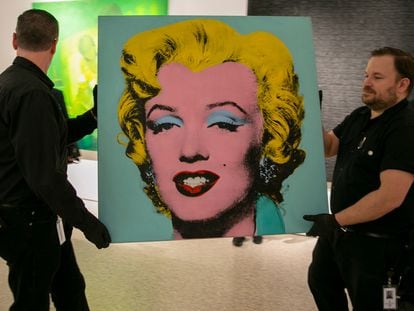 Dos operarios trasladan el cuadro de Warhol, este domingo en la sala de exposiciones de Christie's en Nueva York.