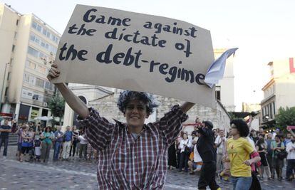 Un aficionado sujeta un cartel durante una actuación callejera: Partido contra el mandato del régimen de la deuda".