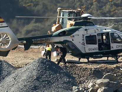 Un agente baja explosivos del helicoptero para los trabajos de excavación.