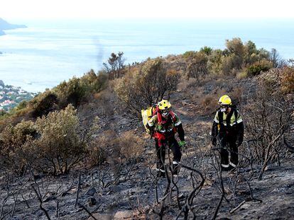 Dos bomberos en un bosque quemado en el incendio de Llançà, en Girona.
