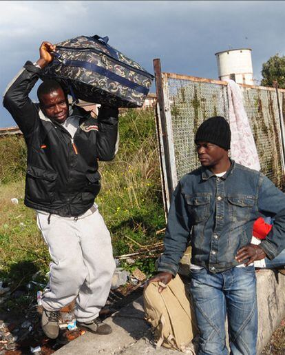 Dos jornaleros africanos, con sus pertenecias, inician la huida de Rosarno.