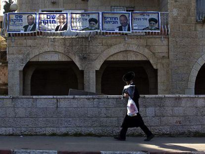 Un joven ultraortodoxo pasa ante una casa decorada con carteles del partido religioso sefard&iacute; Shas, en Jerusal&eacute;n. 