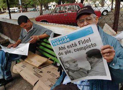 Dos hombres leen el diario <i>Juventud Rebelde,</i> con las imágenes de Castro y Chávez, ayer en La Habana.
