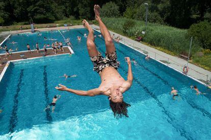 Un joven salta desde el trampolín de una piscina publica en Dresden (Alemania).