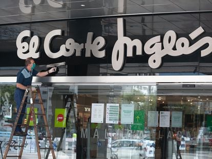 Un trabajador limpia la entrada de uno de los centros de El Corte Inglés en Málaga.