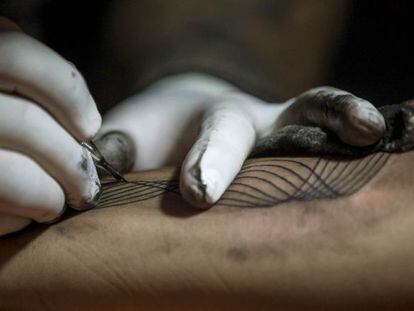CAR34. CARACAS (VENEZUELA), 02/10/2016.- Detalle de un tatuador haciendo un tatuaje hoy, domingo 2 de octubre del 2016, en Caracas (Venezuela). Un conjunto de profesionales del &quot;arte corporal&quot; ofrecen hacer tatuajes a cambio de donaciones de &uacute;tiles escolares para que ni&ntilde;os de bajos recursos econ&oacute;micos puedan comenzar el venidero a&ntilde;o acad&eacute;mico, esto a trav&eacute;s de la jornada llamada &quot;Tatuajes x &uacute;tiles&quot; que se lleva a cabo en Caracas. EFE/MIGUEL GUTI&Eacute;RREZ