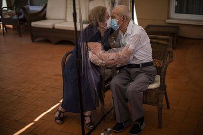 Una pareja de octogenarios besándose a través de una cortina de plástico para evitar el contagio en una residencia de Barcelona