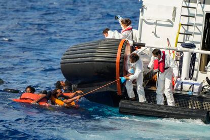 Un migrante se agarra a un palo que le ofrecen miembros de la Guardia Costera italiana para rescatarlo. 