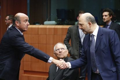 Luis de Guindos, estrecha la mano del comisario Pierre Moscovici en presencia del ministro alem&aacute;n de Econom&iacute;a, Wolfgang Schaeuble.