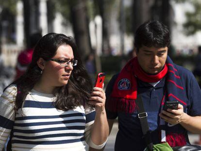 Dos mexicanos consultan su celular en la Ciudad de M&eacute;xico.