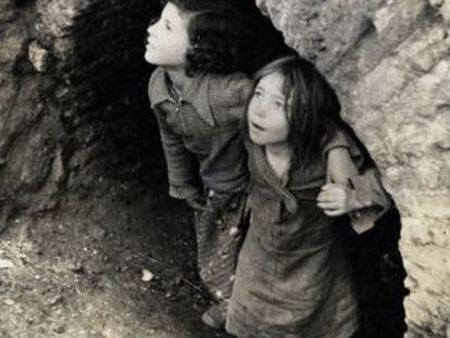 Ni&ntilde;os refugiados bajo un arco de mamposter&iacute;a en la Guerra Civil.