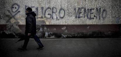 Un vecino pasa ante una pintada contra el lindano en las viviendas sociales de Torneiros (O Porriño).