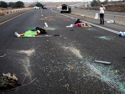 Un hombre toma una foto de varias de las víctimas del ataque de Hamás en una carretera cercana a la ciudad meridional israelí de Sderot.