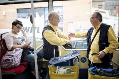 Juan Tamayo (izquierda) habla con su compañero Javier en el autobús que les lleva a su zona de reparto.