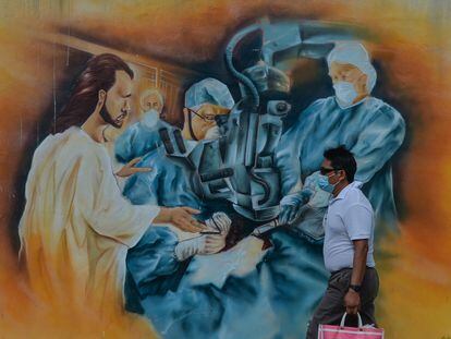Un hombre camina junto a un mural relacionado con la pandemia de covid-19 en el centro de Mérida, Yucatán.