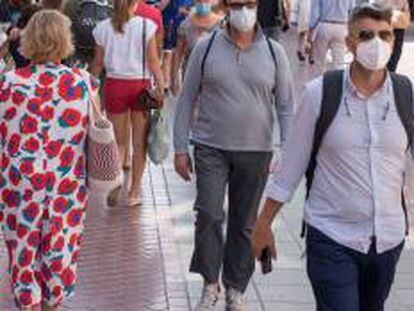 Rranseúntes se protegen con mascarillas por las calles.  .