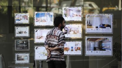 Un joven mira anuncios de alquiler de una inmobiliaria en Barcelona.