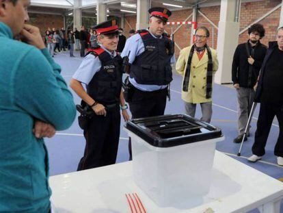 Dos 'mossos' ante una urna de un colegio durante la jornada del referéndum del 1 de octubre en Cataluña. En vídeo, las claves de la sentencia.