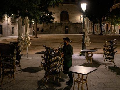 Un camarero recoge la terraza de un bar en la plaza de la Paja de Madrid.