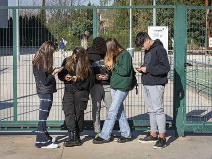 Adolescentes, en la puerta de un centro escolar en Valencia, con sus móviles.