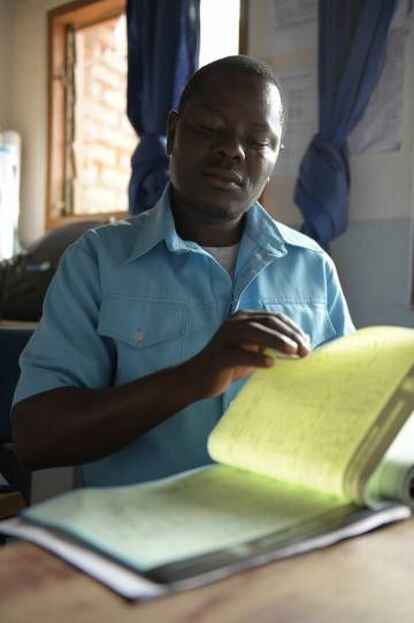 El trabajador de salud Dennis Nkuma abre un libro de registro de vacunas en un centro de salud en el sur de Malawi.