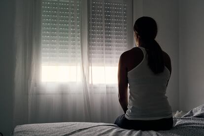 Una mujer observa la ventana desde su habitación