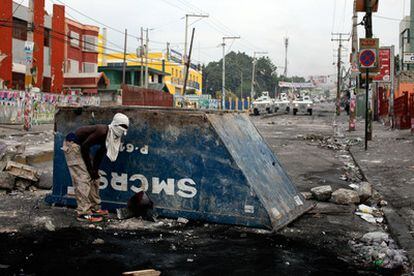 Un hombre se refugia detrás de una barricada durante las protestas contra los resultados electorales, y que enfrentaron a haitianos y cascos azules en las inmediaciones del Consejo Electoral Provisional.