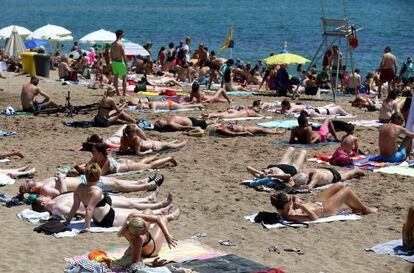 Banyistes prenent el sol a la platja de la Barceloneta.