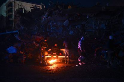 Un grupo de ciudadanos se calienta en una hoguera entre los escombros de los edificios derrumbados en la ciudad turca de Kahramanmaras este martes.