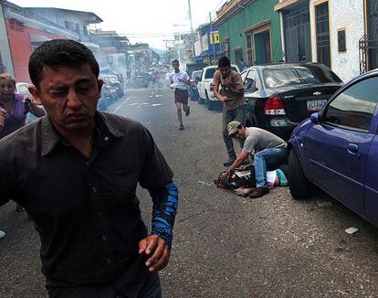 Un hombre atiende al joven tiroteado el lunes durante una protesta en Venezuela.