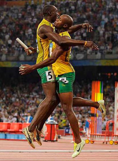 Usain Bolt (izquierda) y Asafa Powell festejan el tercer oro jamaicano en las pruebas de velocidad.