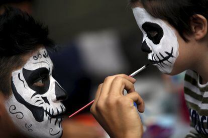 En la Ciudad de México se celebra un desfile de catrines y catrinas. Se ve a hombres y mujeres con los rostros pintados.