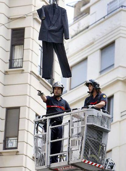 Los bomberos retiran un traje colgado ayer en una calle de Valencia.
