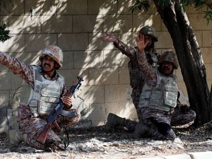 Tres militares paquistaníes se cubren durante el ataque al consulado chino en Karachi (Pakistán).