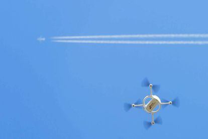 Un dron vola sota el rastre d'un avió comercial.