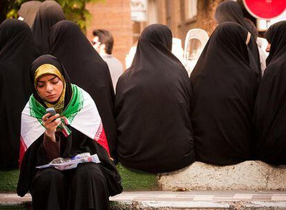 Una joven cubierta con la bandera de Irán usa su móvil el pasado 16 de junio en Teherán.