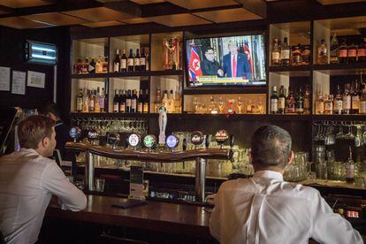 Dos personas siguen en la televisión de un bar de Singapur la reunión.