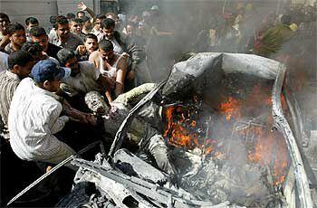 Varios palestinos tratan de extraer de un vehículo el cuerpo carbonizado del dirigente de Hamás asesinado ayer en Gaza.
